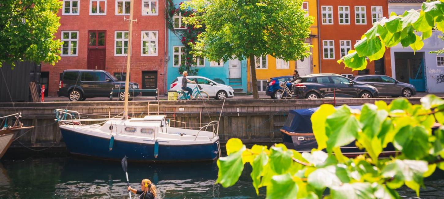 Woman kayaking past coloured houses in Christianshavn