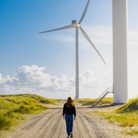 Woman walking towards a windmill at Hvide Sande, Jutland